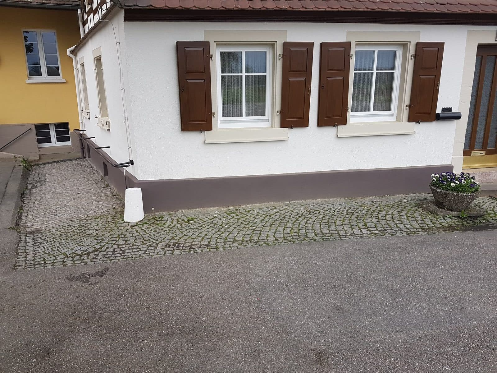 Odświeżona elewacja domu z okiennicami po malowaniu
